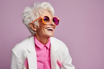 Portrait of a smiling senior woman in sunglasses. Isolated on purple background.