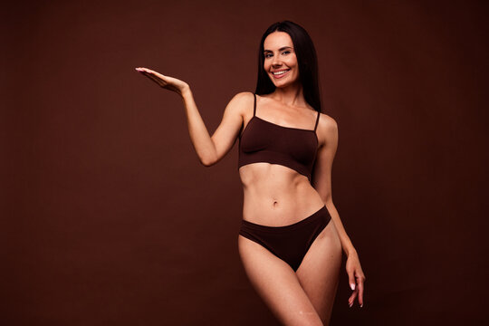 Photo portrait no filter of attractive young woman palm hold empty space dressed stylish underwear isolated on brown color background