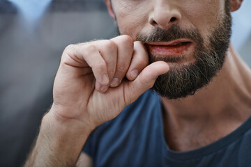 cropped view of anxious man with beard biting his lips till blood during depressive episode