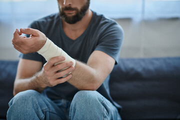 cropped view of depressed man with bandage on arm after attempting suicide, mental health awareness