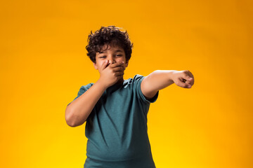 Kid boy laughing at somebody and pointing finger at camera. Bulling concept - obrazy, fototapety, plakaty