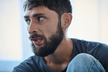 Obraz premium ill traumatized man with beard biting his lips during depressive episode, mental health awareness