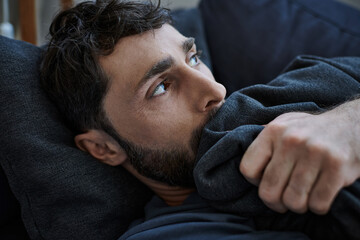 Obraz premium depressed bearded man in casual outfit lying on sofa during breakdown, mental health awareness