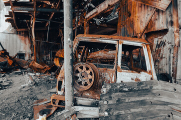 burnt car on the street of the ruined city