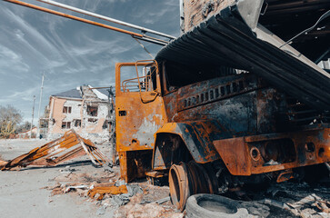 Fototapeta premium burnt military armored car on the street of the ruined city