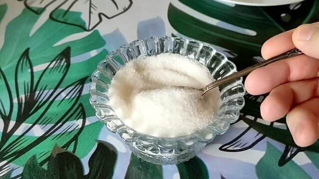 Man stirs sugar in a sugar bowl with a spoon