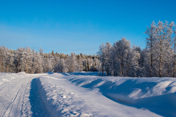Fototapeta premium Idyllic panoramic view of a beautiful white winter wonderland scenery in Scandinavia with scenic golden evening light at sunset in winter, northern Europe.