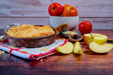 Freshly baked apple pie on a rustic kitchen worktop with ingredients and kitchen utensils.