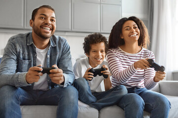 Happy Black Preteen Boy Playing Video Games With His Parents At Home