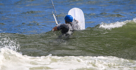 Man in the ocean holding a board ready to begin kiteboarding