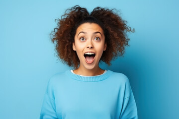 Surprised young pretty woman looking at the camera isolated on blue background.