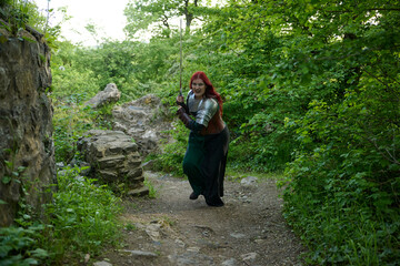 Mittelalterliche Frau mit Rüstung und roten Haaren als Kriegerin mit Kriegsbemalung mit Schwert im...