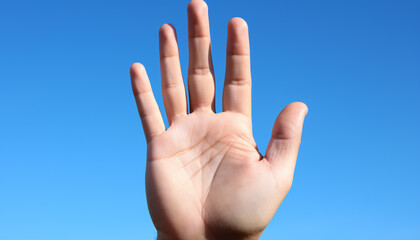 Human hand gesturing a sign of success under clear blue sky generated by AI