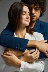 Man gently embracing woman from behind, embodying the concept of care and affection in a couple