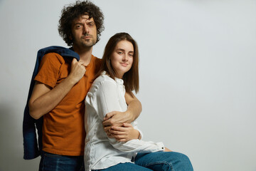 Family portrait of young couple against white backdrop. Woman smiling at the camera, the man with displeased emotions - 730141340