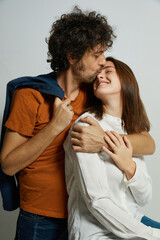Portrait of young passionate couple cheerfully embracing and kissing against a clean white background - 730141569