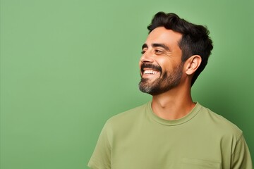 Portrait of a handsome young man laughing against a green background.