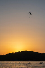 Silhouette of paraglider over the sea during sunset