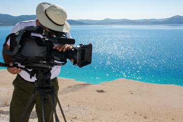 A cameraman filming a documentary with a camera at Salda Lake in Turkey.