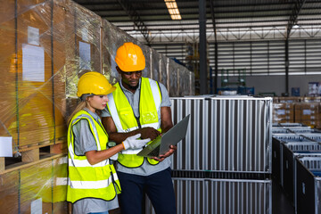 Black factory worker man and young Caucasian woman co worker looking at tablet working in warehouse