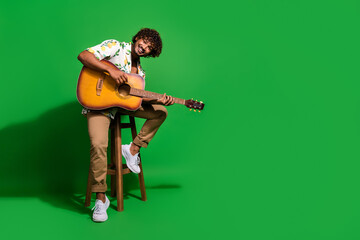 Full length photo of handsome young guy sit chair playing guitar dressed stylish citrus print...