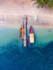 Muelle con botes coloridos en playa con aguas cristalinas 