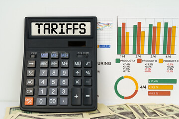 On the table are financial reports, dollars and a calculator with the inscription - Tariffs