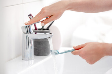 Girl'S Hand Holds Toothbrush Under Water Stream In Bathroom In The Morning