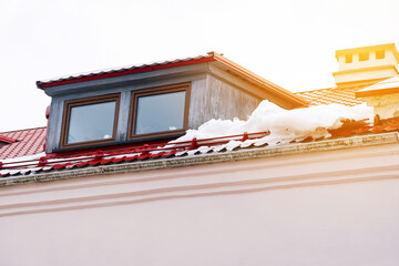 Red roof covered with snow. Roof drain and protection from snow. Snow guard rails on metal roof....
