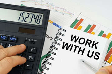 On the table there is a calculator, reports with graphs and a notepad with the inscription - WORK...