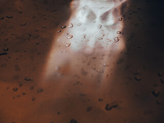 Water drops on silver aluminum background with brown reflections for a mysterious abstract...