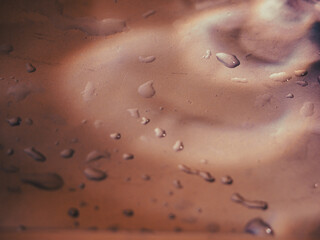 Fototapeta premium Water drops on silver aluminum background with brown reflections for a mysterious abstract background.