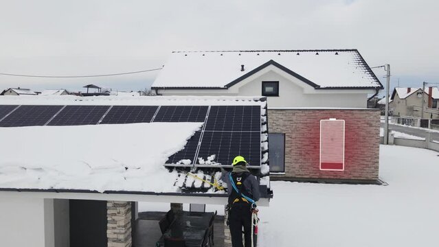 Smart House With Low Battery Icon In Winter. Technician Repairing Solar Panels On Roof Damaged By Snow. drone sideways