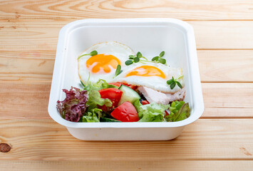 Fried eggs and turkey. Healthy diet. Takeaway food.  On a wooden background.