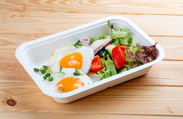 Fried eggs and turkey. Healthy diet. Takeaway food.  On a wooden background.