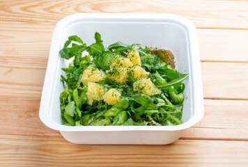 Salad of arugula, carrots and orange. Vegetarian food. Takeaway food. On a wooden background.