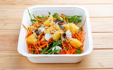 Carrot salad with orange. Healthly food. Takeaway food. On a wooden background.