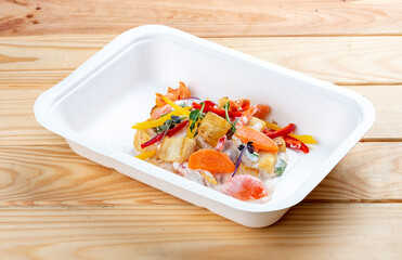Hake fricassee with vegetables. Healthy diet. Takeaway food.  On a wooden background.
