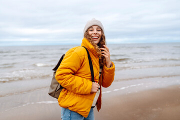 Happy tourist in a yellow jacket and with a backpack  posing by the sea.  Travelling, lifestyle, adventure.