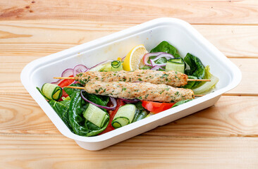 Chicken lula kebab with herbs and vegetables. Healthy food. Takeaway food. On a wooden background.