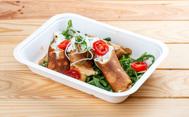 Caneloni with ricotta cheese and spinach. Takeaway food. On a wooden background.