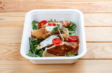 Caneloni with ricotta cheese and spinach. Takeaway food. On a wooden background.