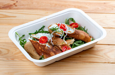 Caneloni with ricotta cheese and spinach. Takeaway food. On a wooden background.