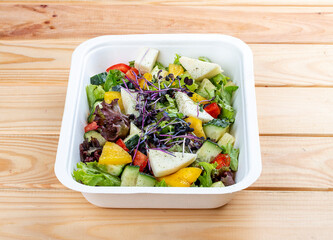 French salad with Camembert cheese. Healthy food. Takeaway food.  On a wooden background.