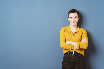 Confident Young Businesswoman with Short Hair Smiling Against Blue Wall with Copy Space