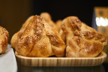 Freshly prepared pastries in a bakery. Golden small pies with chicken meat and potatoes, kurnik on wooden plate. Food background, snacks in coffee shop. © Sea_Inside_Soul