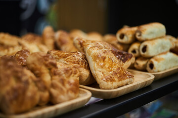 Varied selection of pastries and snacks in coffee shop. Golden puff pastry baked in the oven. Samsa, sausages in dough, kurnik. Bakery delicious food background, national cuisine of Asian countries. © Sea_Inside_Soul