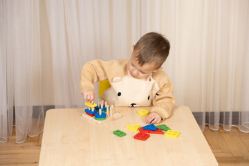 A two-year-old boy plays with wooden toys to develop logic and motor skills