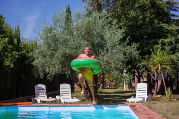 Man in his forties jumps into pool with big inflatable ring
