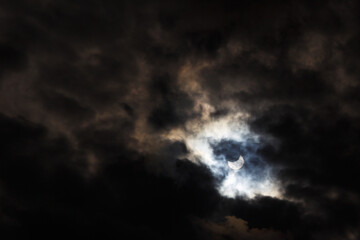A partial solar eclipse of October 25, 2022 captured through moody dark clouds, the maximal phase...